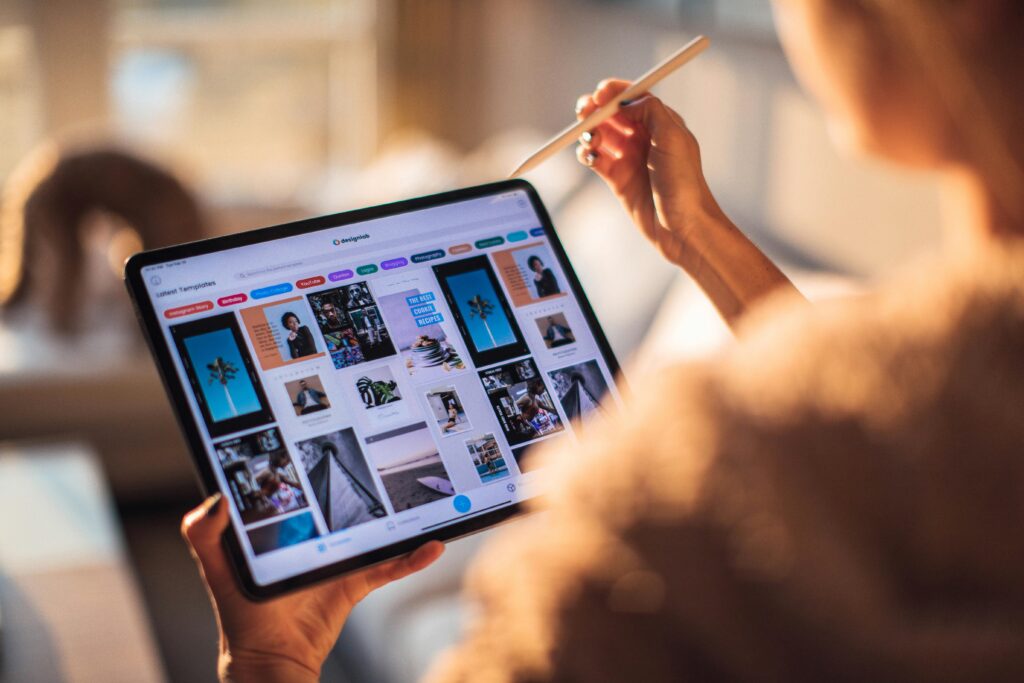 A person uses a digital tablet with a stylus indoors in a warm, cozy setting.